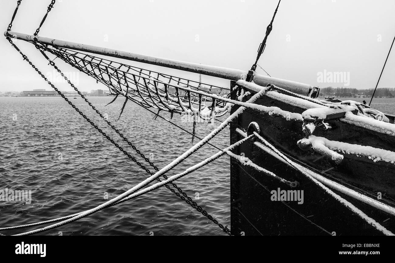 Houseboat con bompresso e la prua e la vista del porto di Amsterdam con la neve in B&W Foto Stock