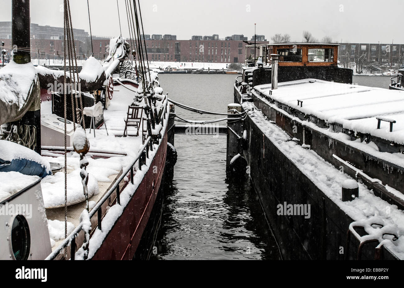 Due case-barche a vela ormeggiate e coperto di neve nel porto di Amsterdam Foto Stock