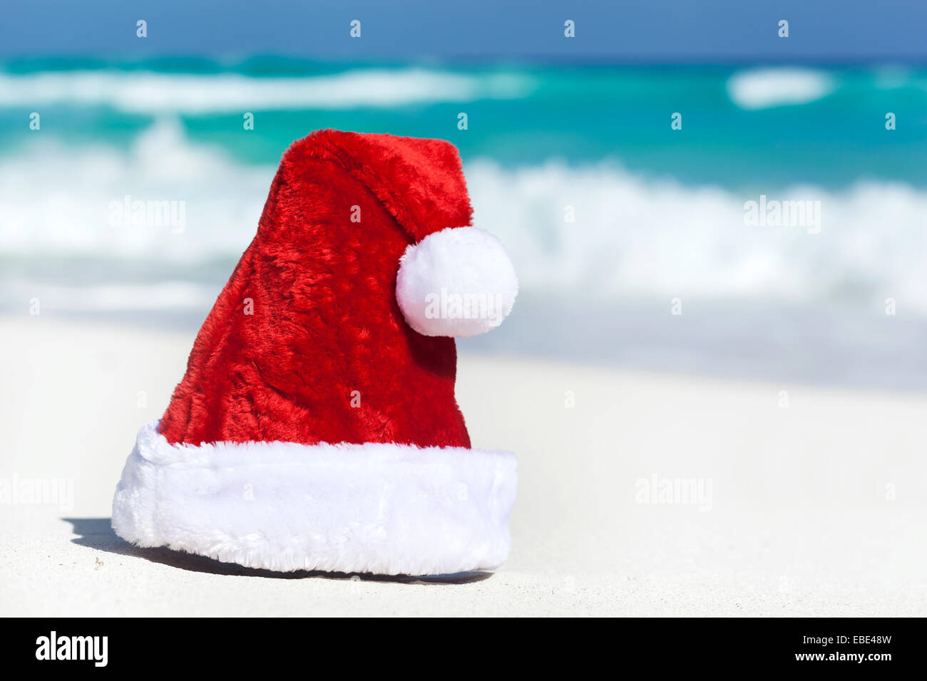 Santa Hat sulla spiaggia di sabbia bianca sul Mar dei Caraibi sfondo Foto Stock