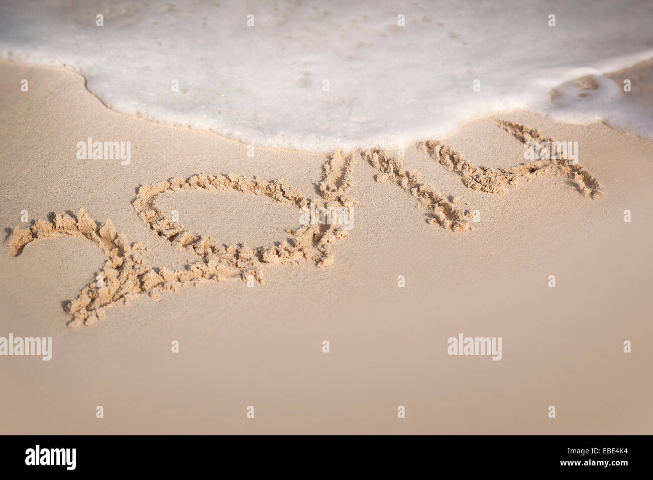 Iscrizione 2014 sulla spiaggia di sabbia con onde di schiuma, copyspace libero Foto Stock