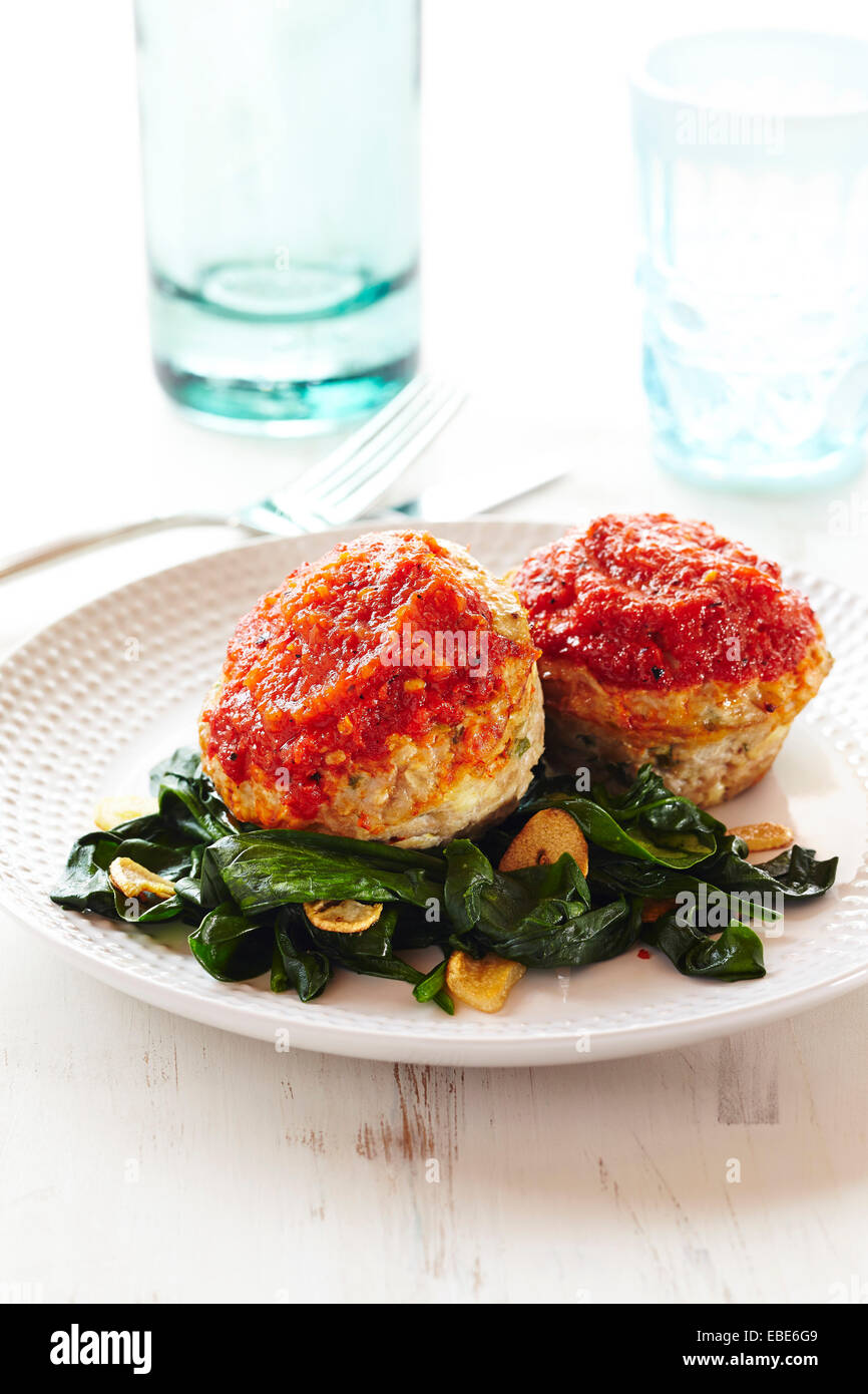 Mini Turchia focacce al sugo su appassì gli spinaci in bianco sullo sfondo di legno, Studio Shot Foto Stock