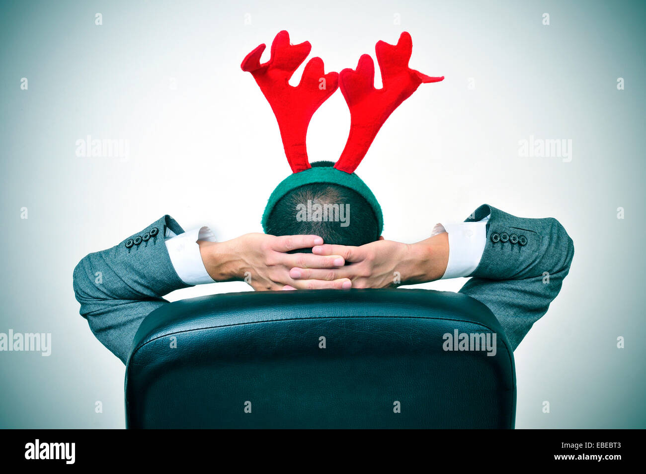 Un uomo con una renna palchi con archetto rilassante nella sua sedia per ufficio dopo un ufficio Christmas party Foto Stock