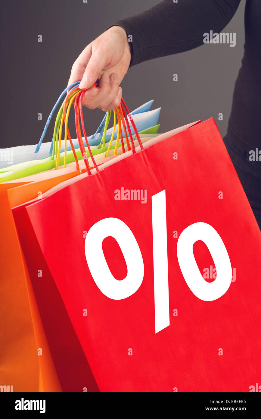 Donna che mantiene colorata borse per lo shopping con percentuale di segno stampato su per i prezzi di sconto acquisto stagionale evento. Foto Stock