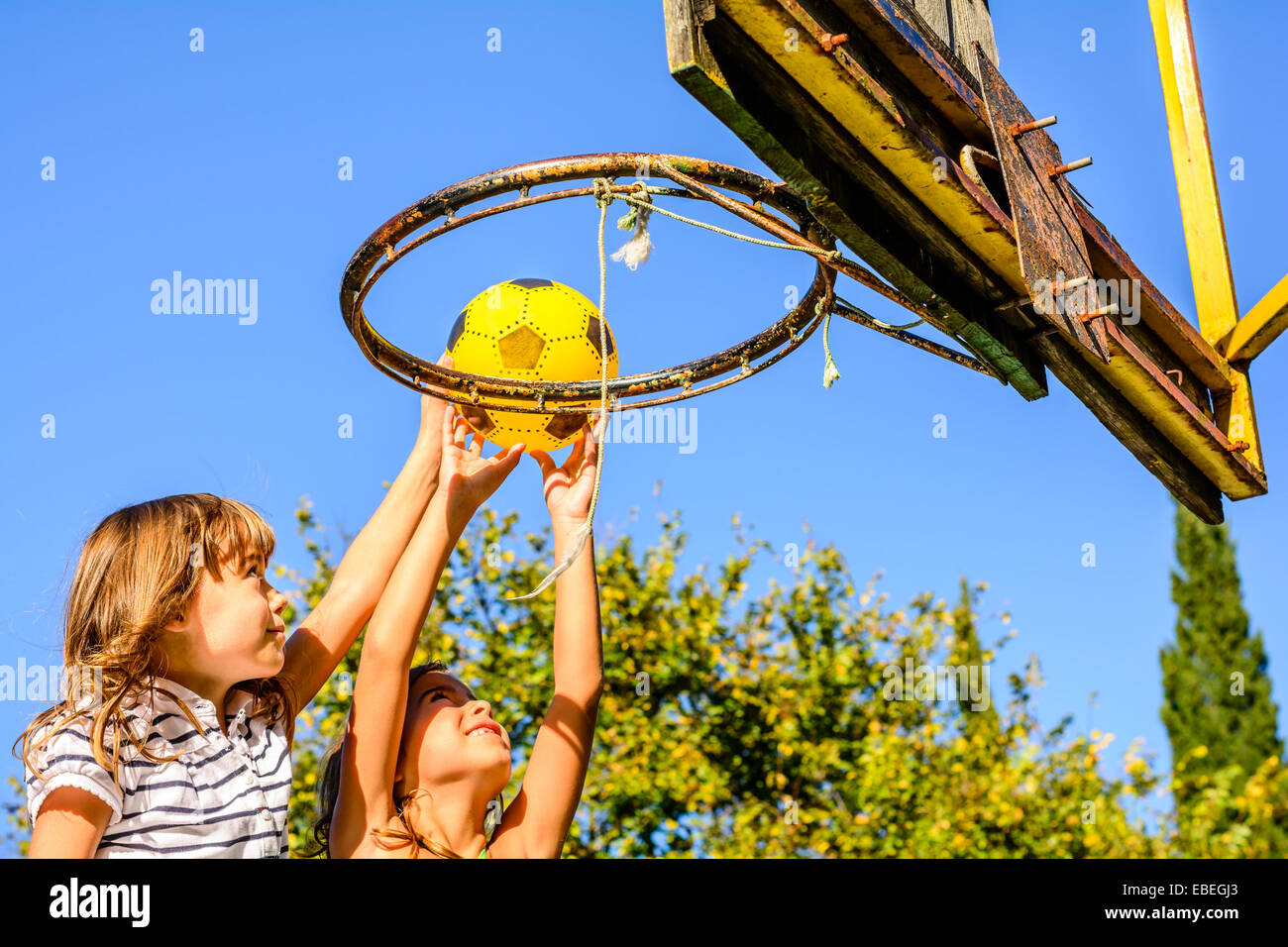 Due di sette anni le ragazze giocare a basket all'aperto Foto Stock