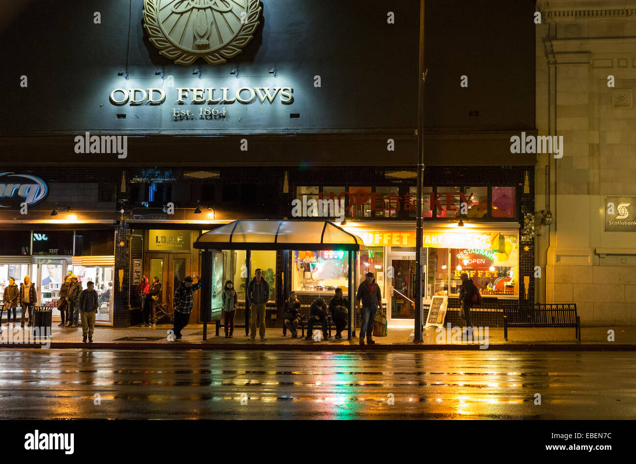 Persone in attesa alla fermata del bus in downtown Victoria sulla notte piovosa-Victoria, British Columbia, Canada. Foto Stock