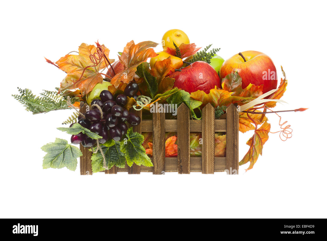 Composizione dalla Frutta artificiale e foglie di autunno in cassetta di legno isolato su sfondo bianco. Primo piano. Foto Stock