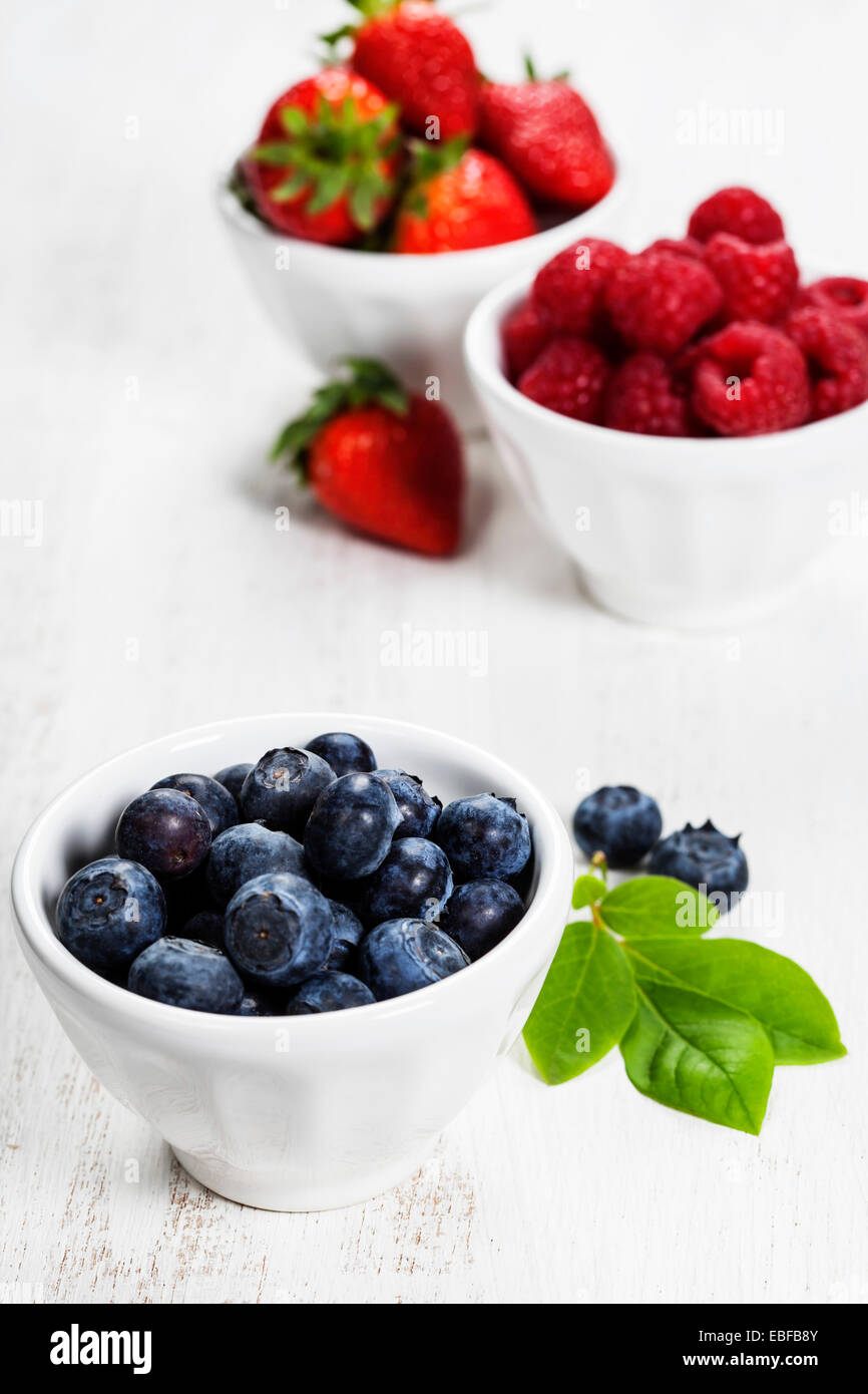 Bacche di bocce su sfondo di legno. Fragole, lamponi e mirtilli. La salute, la dieta, giardinaggio, concetto di raccolto Foto Stock