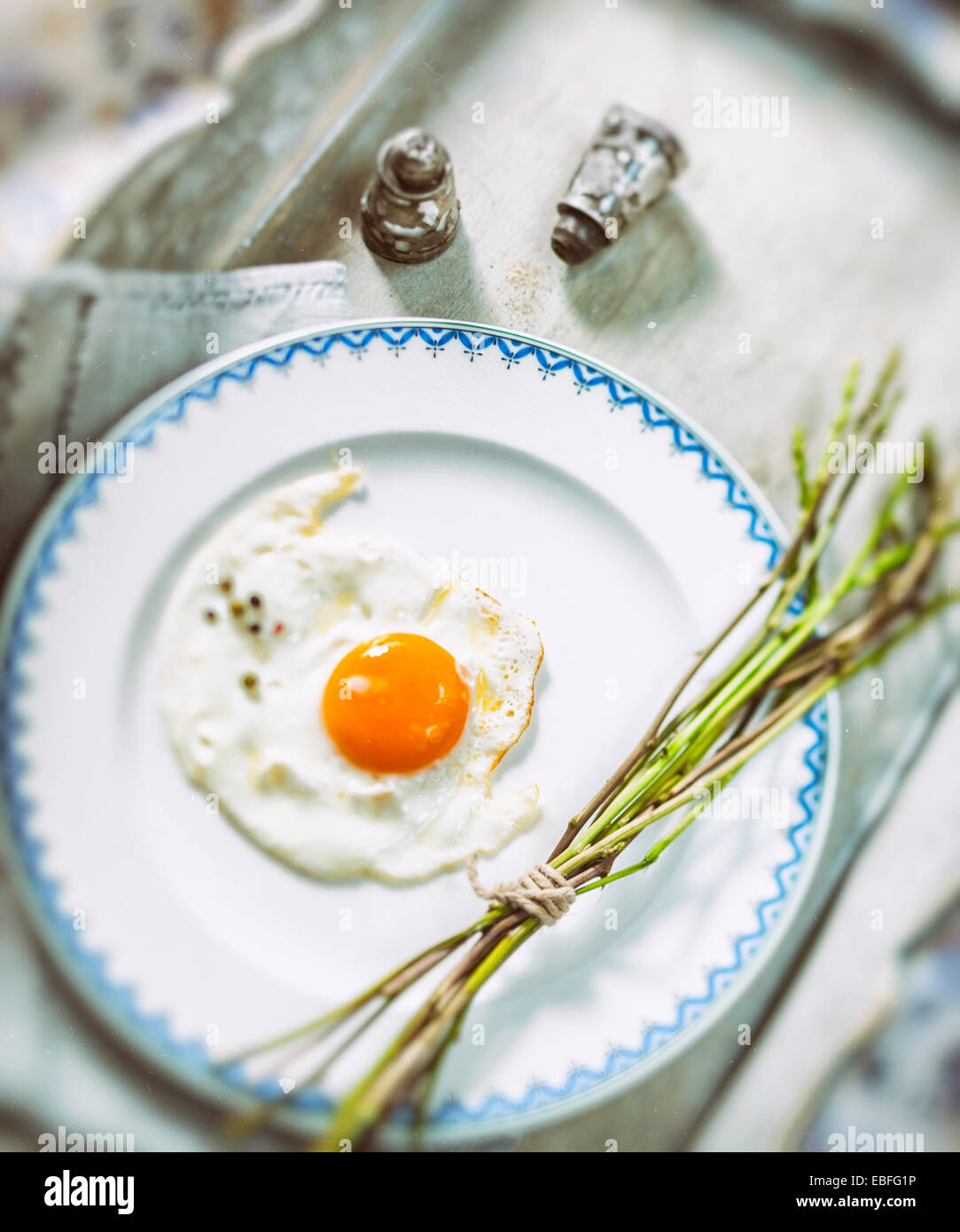 Uovo fritto e freschi asparagi selvatici su una piastra bianca Foto Stock
