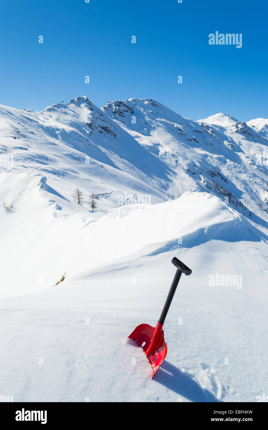 Rosso pala a valanga in polvere di neve fresca. Scenic nevato alta montagna sfondo. Stagione invernale nelle Alpi italiane. Foto Stock