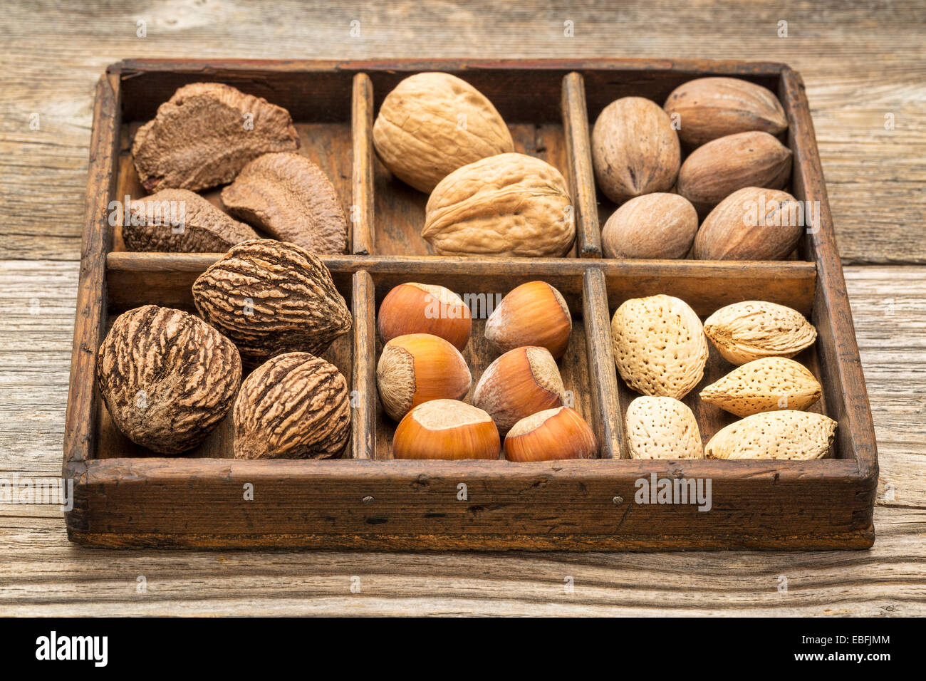 Una varietà di dadi (noce pecan, nocciola, Brasiliano e mandorla) +in un rustico di scatola di legno Foto Stock