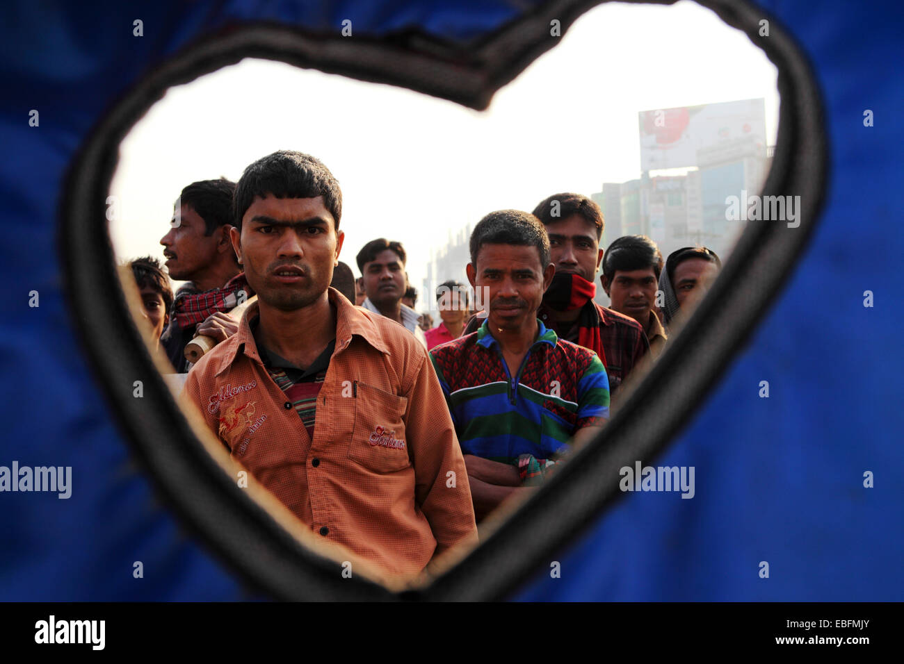 La gente in una strada a Dacca in Bangladesh. Essi sono visibili attraverso la forma di cuore di un rickshaw tettoia. Foto Stock