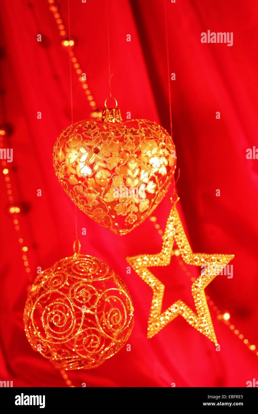 Golden decorazioni di Natale sulla stoffa rossa sullo sfondo Foto Stock