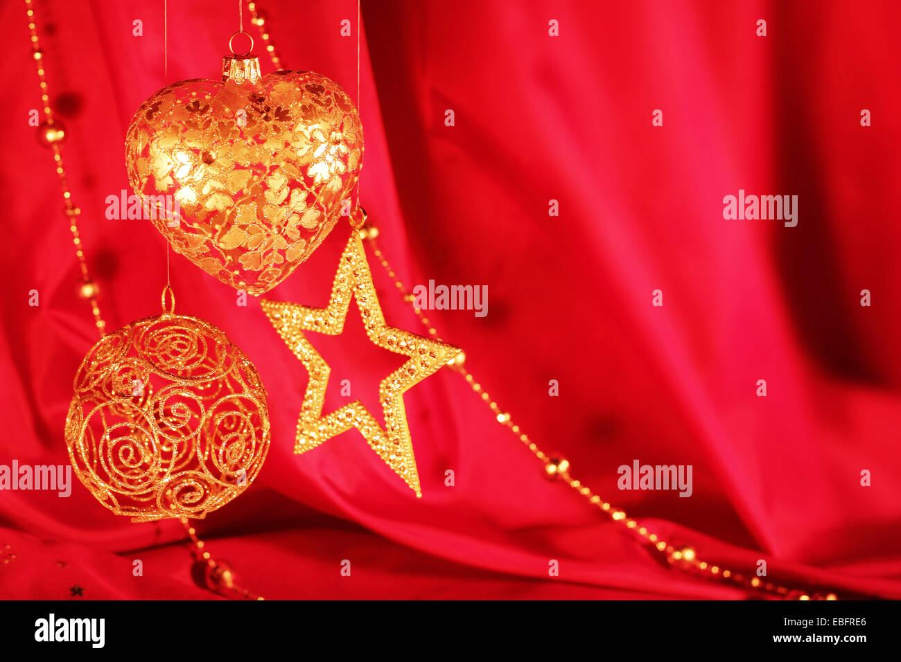 Golden decorazioni di Natale sulla stoffa rossa sullo sfondo Foto Stock