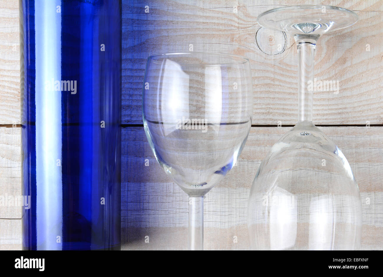 Alta angolazione di un blu bottiglia di vino e due bicchieri di vino in un ambiente rustico in legno bianco tavola. Formato orizzontale. Foto Stock