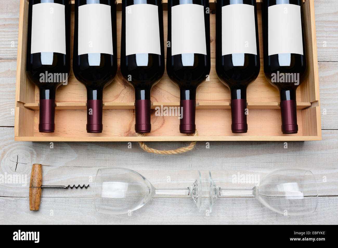 Tettuccio di colpo di un caso di bottiglie di vino rosso con etichette vuote su un rustico di legno bianco tavola con bicchieri di vino e vite di sughero bel Foto Stock