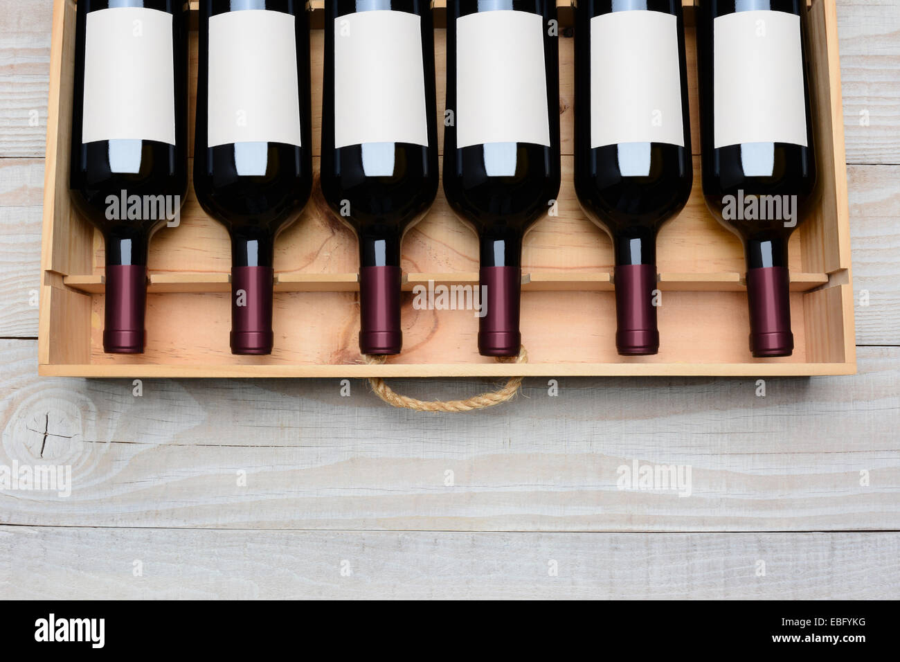 Tettuccio di colpo di un caso di bottiglie di vino rosso con etichette vuote su un rustico di legno bianco tavola con copia dello spazio sul fondo. Orizz. Foto Stock