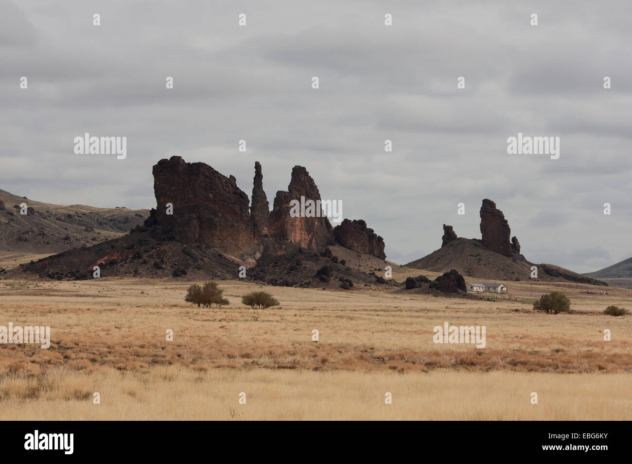 Dimora isolata vicino ad alcune scure dighe vulcaniche. Dilkon, Navajo Land, Arizona, Stati Uniti. Foto Stock