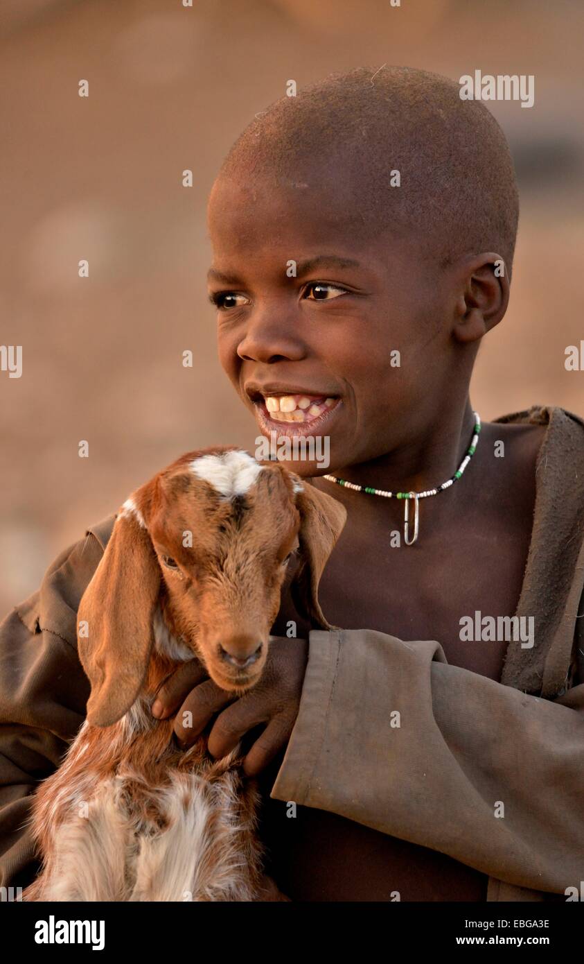 Himba ragazzo con una capra, Ombombo, Kaokoland, Kunene, Namibia Foto Stock