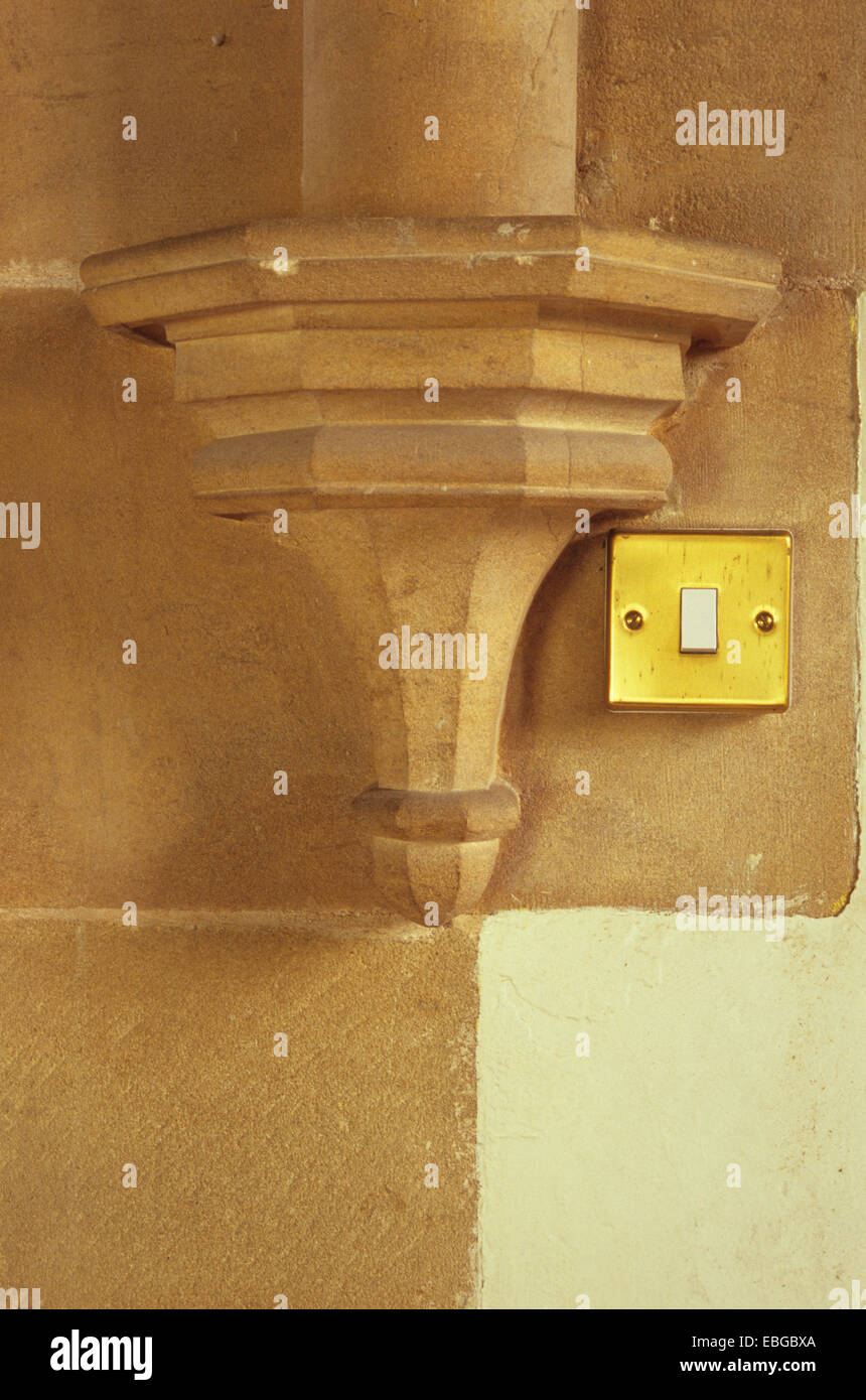 Victorian pietra intagliata corbel e muro di pietra con color oro interruttore luce il raccordo avvitato accanto ad esso Foto Stock