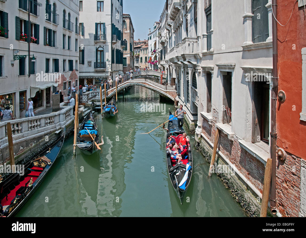 Ponte sul canal Rio de la Canonica e gondalas con gondalier e sole Venezia Italia Foto Stock