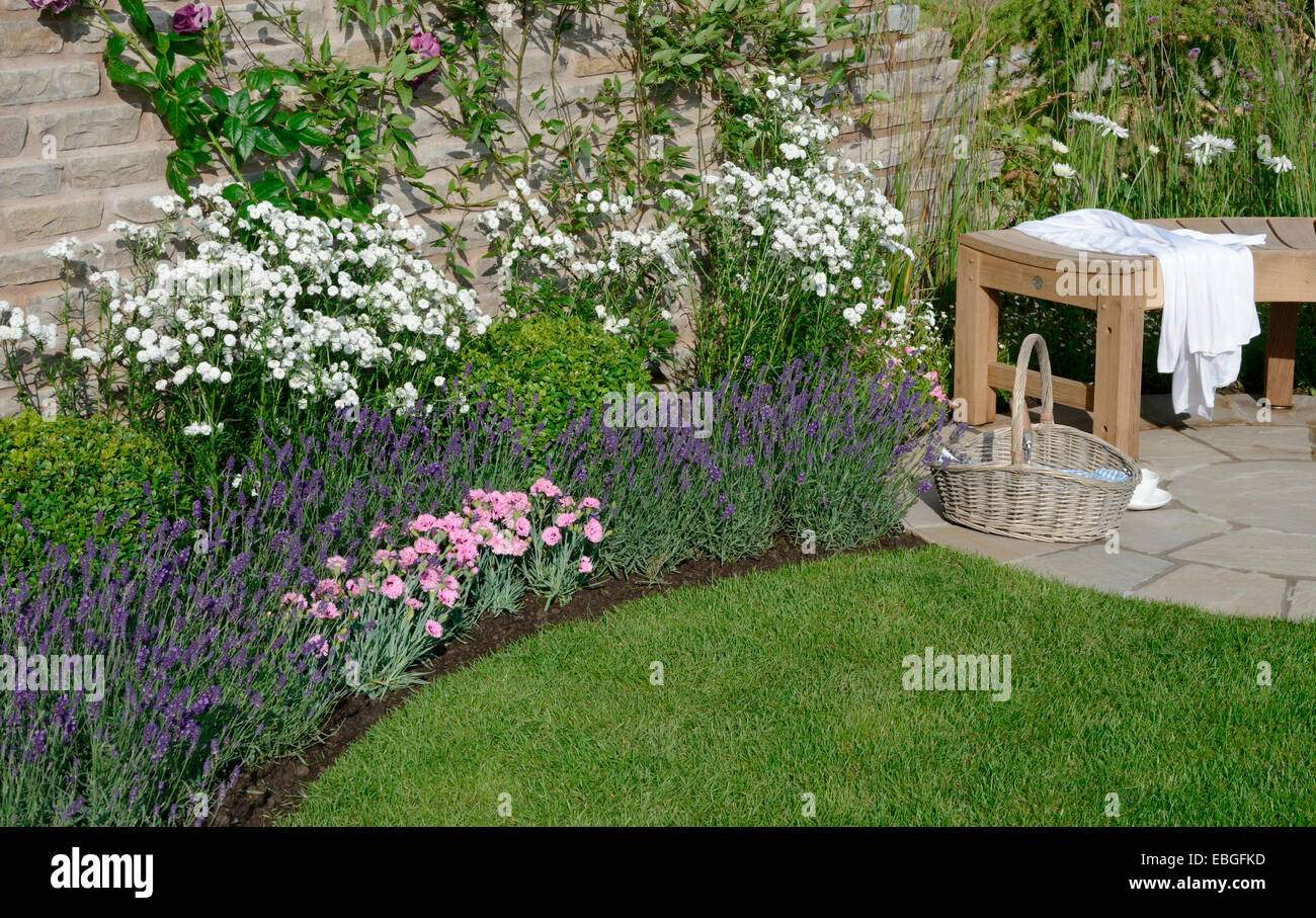 Un fiore di confine e posti a sedere in un angolo di un walled garden cottage Foto Stock