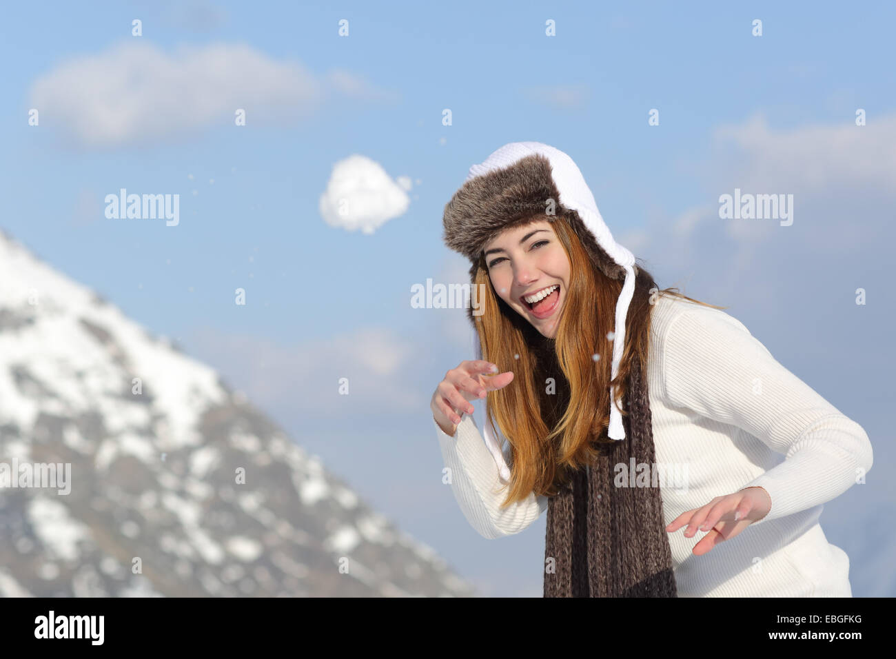 Giocoso donna di gettare una palla di neve in inverno vacanze in una montagna innevata Foto Stock