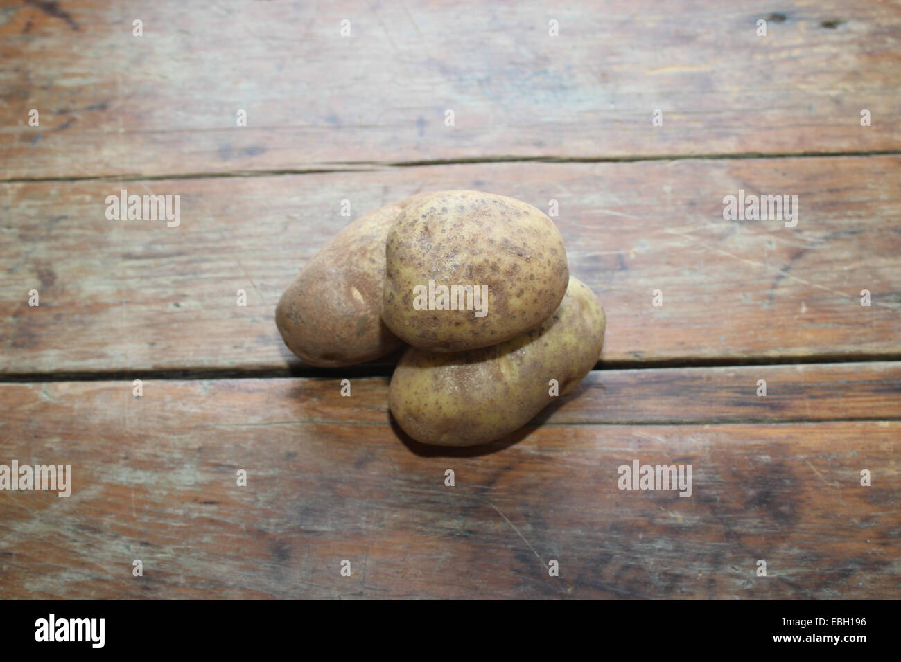 Tre materie patate impilati su un vecchio, distressed tavolo in legno. Foto Stock