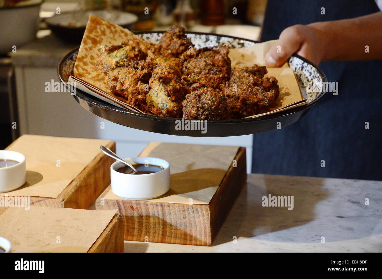 Una mano dello chef visualizzando un piatto di bietola frittelle pronto per la mise en place Foto Stock