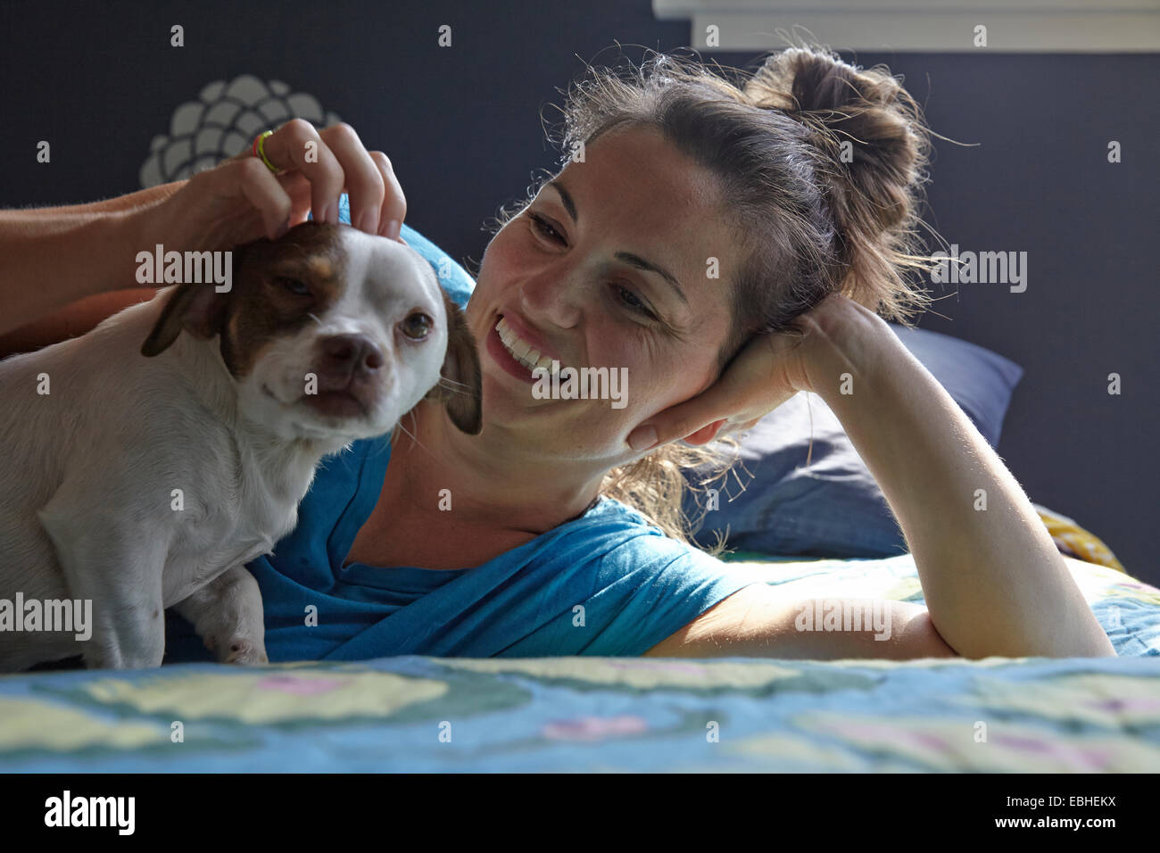 Donna sdraiata sul letto petting cane Foto Stock