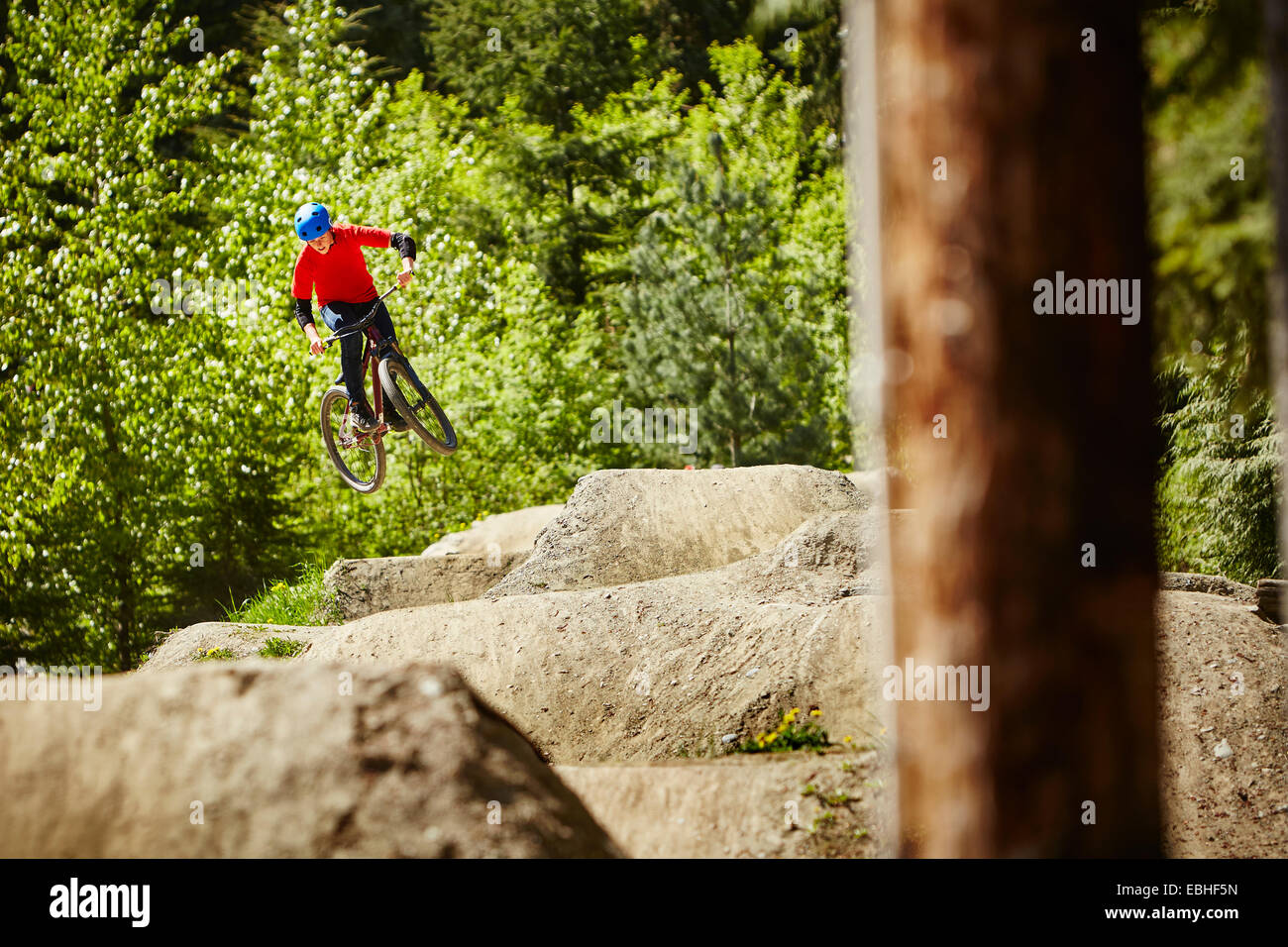 Femmina e giovane biker bmx jumping metà aria dalle rocce in foresta Foto Stock