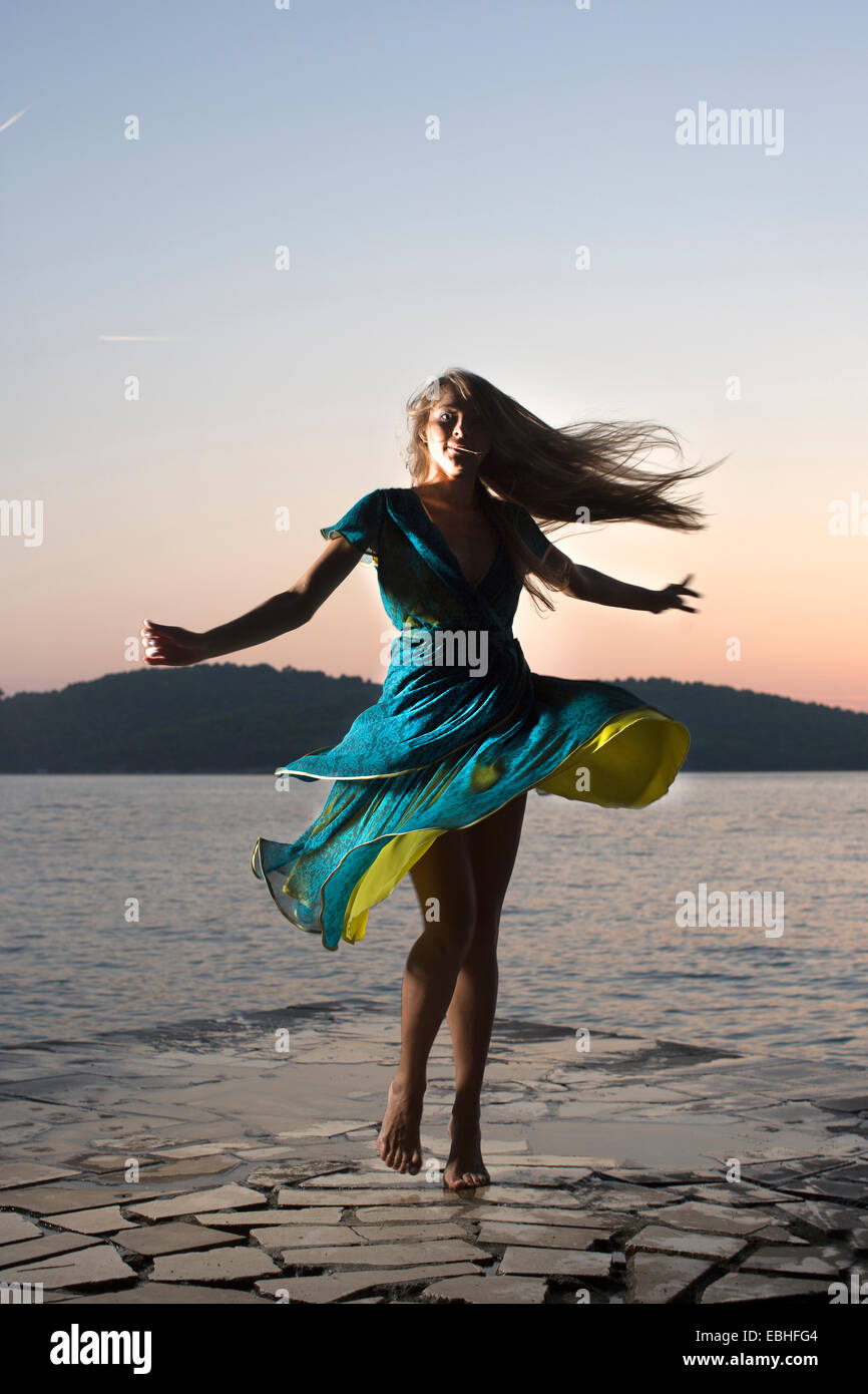 Giovane donna di girare intorno sul lungomare al tramonto, Milna, Brac, Croazia Foto Stock