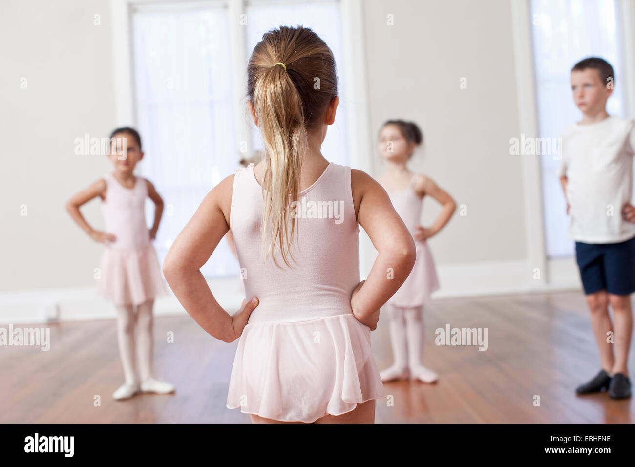 Quattro bambini la pratica di balletto con le mani sui fianchi in scuola di danza Foto Stock