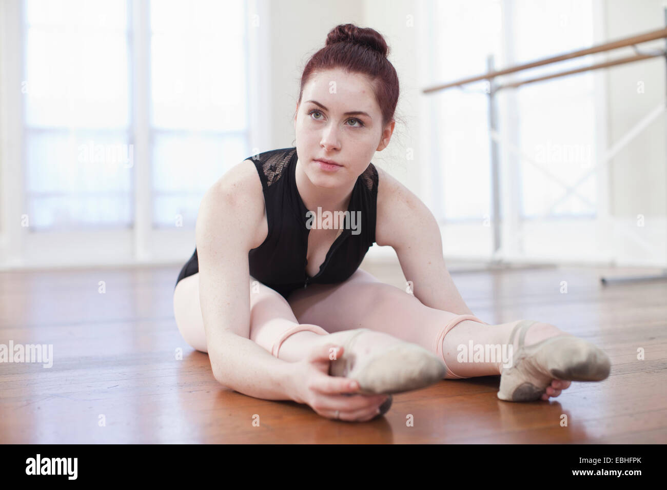 Teenage ballerina seduta sul pavimento in posizione di balletto a scuola di danza Foto Stock