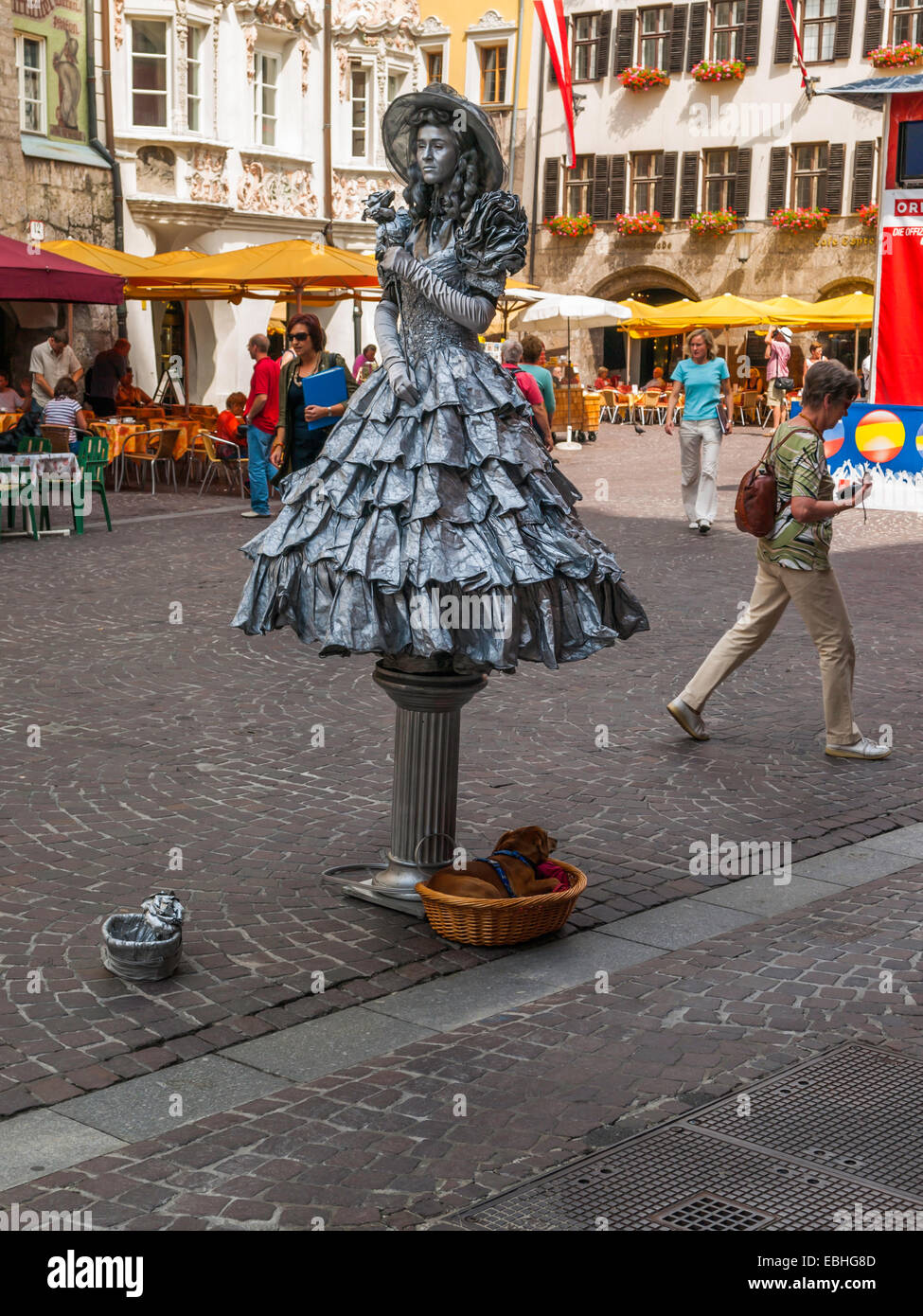 Una donna che si presentano come un molto elaborate live statua vivente in equilibrio su un pilastrino di Innsbruck nel centro città in Austria Foto Stock