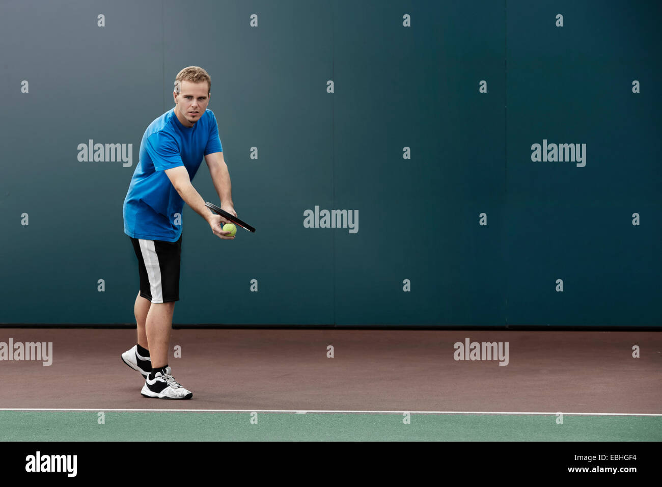 Giocatore di Tennis circa a servire palla in campo da tennis Foto Stock