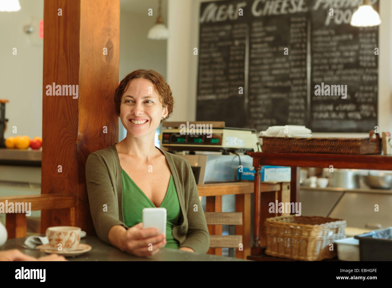 Metà donna adulta con lo smartphone nel paese store cafe Foto Stock