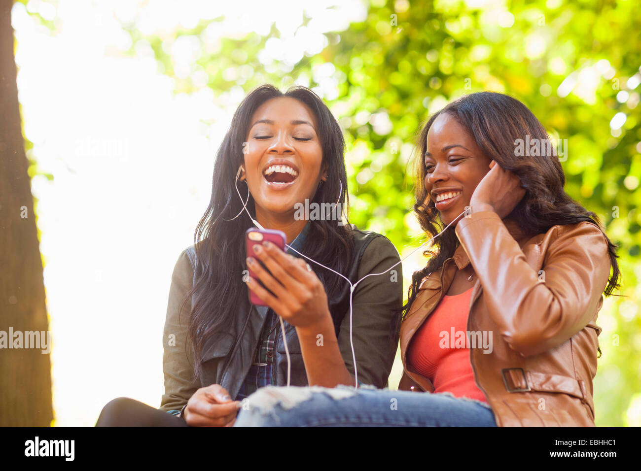 Giovani donne utilizza lo smartphone insieme in posizione di parcheggio Foto Stock
