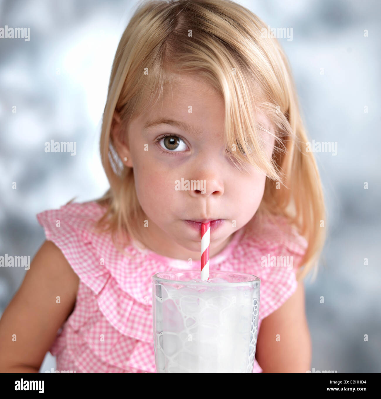 Ritratto di donna toddler soffiare bolle nel latte attraverso la cannuccia per bevande Foto Stock