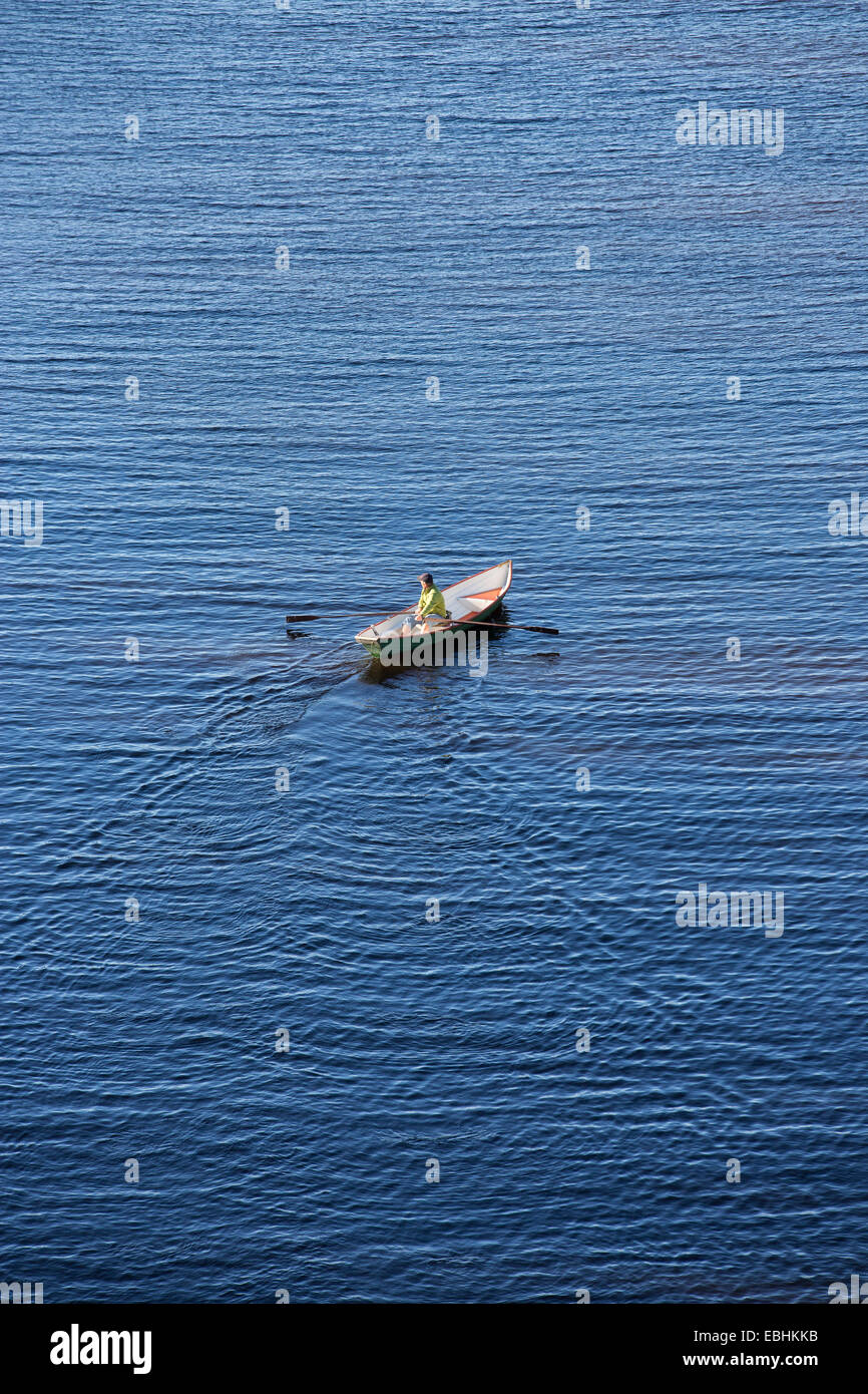 Vista aerea di un anziano che rema una barca a remi in vetroresina / skiff / dinghy , Finlandia Foto Stock