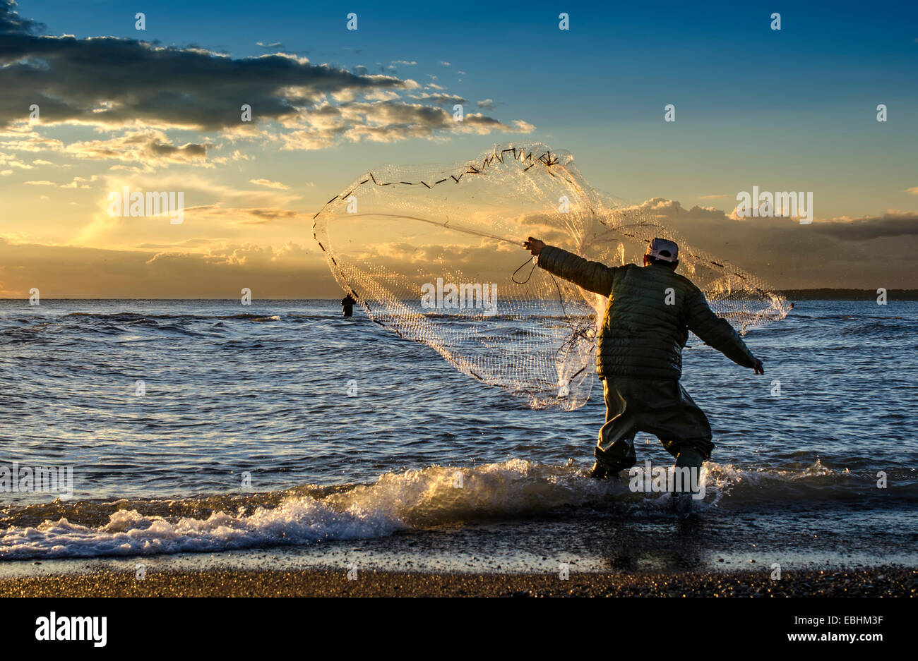 Il pescatore di gettare la pesca net durante il tramonto in Grecia Foto Stock