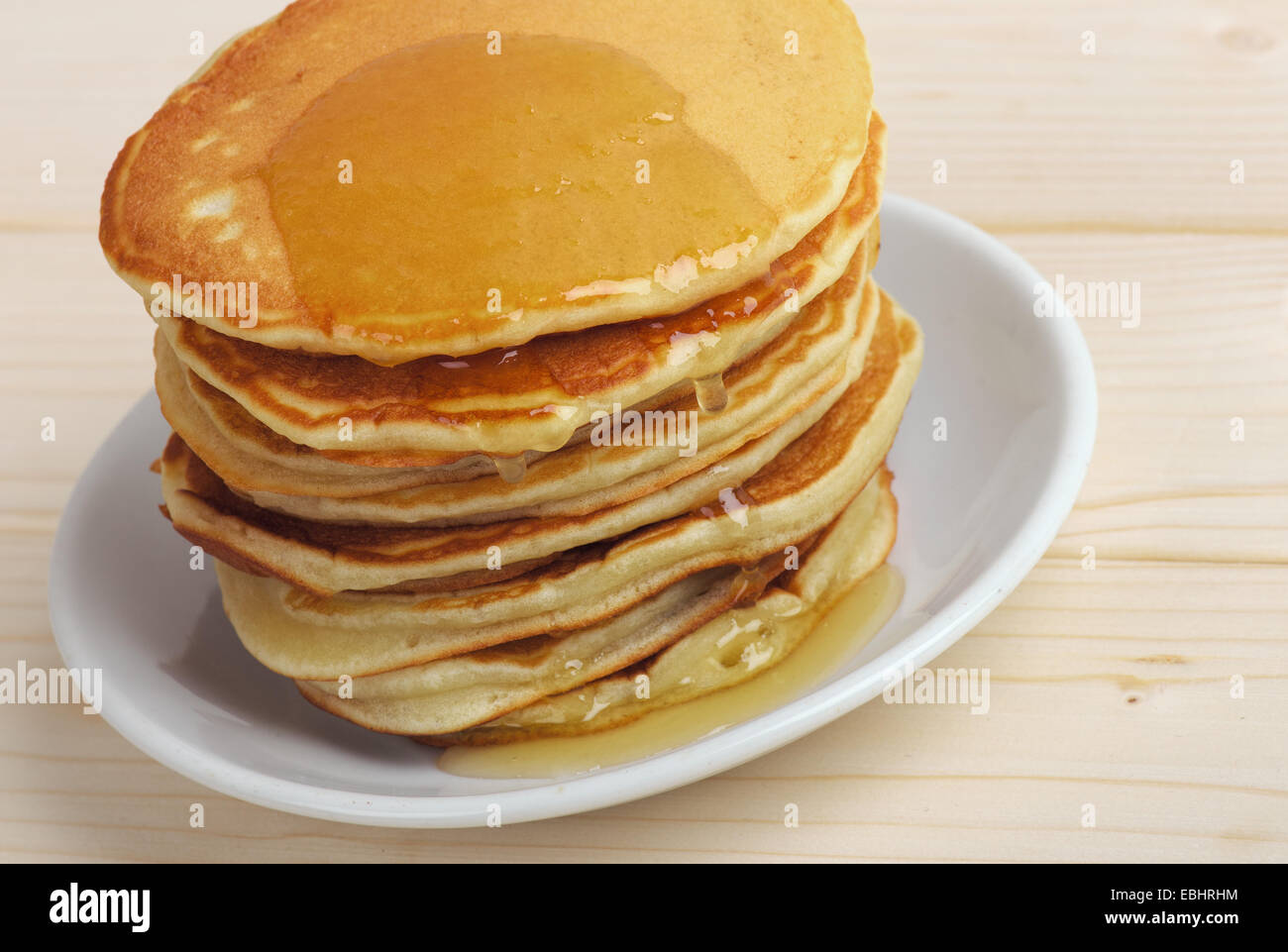 Deliziose frittelle con miele su una tavola fatta di assi di legno Foto Stock