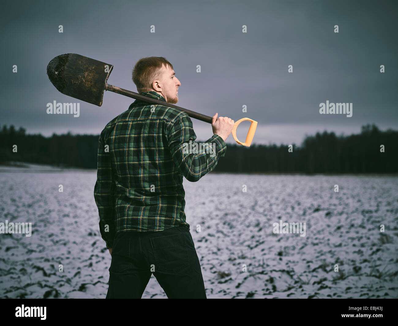 Bel giovane e la pala, snowy campo arato sul background - Croce immagine elaborata Foto Stock