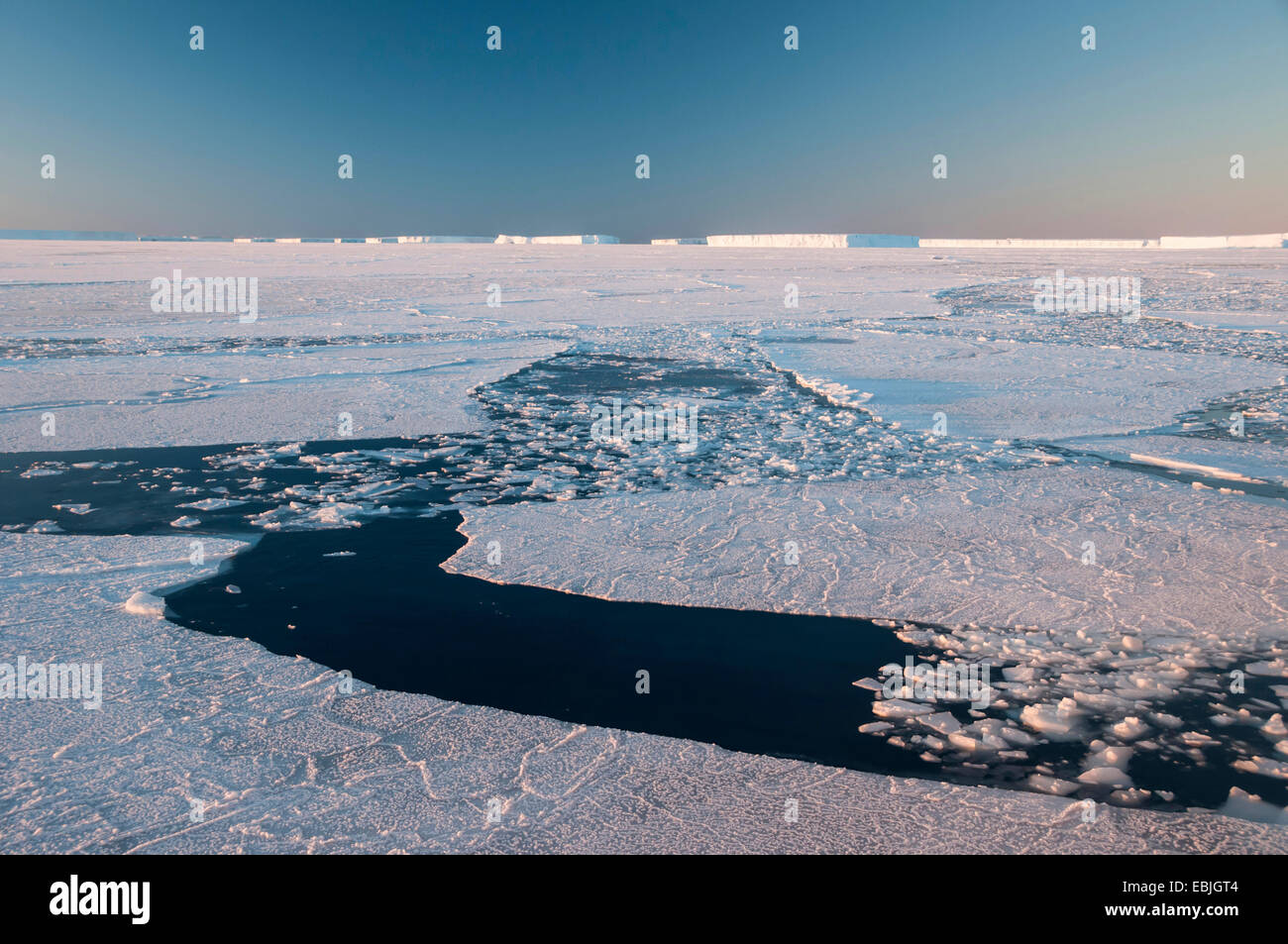 Vie navigabili attraverso la banchisa campo aperto da rompighiaccio in condizioni estreme di gelo vicino a un iceberg luogo di riposo Austasen presso sunrise, Antartide Foto Stock