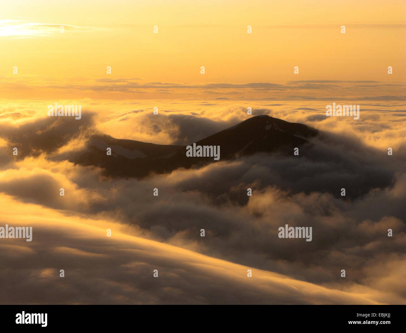 Cime fuoriescono delle nubi nel sole di mezzanotte durante l'approccio per un atterraggio, Norvegia Isole Svalbard Foto Stock