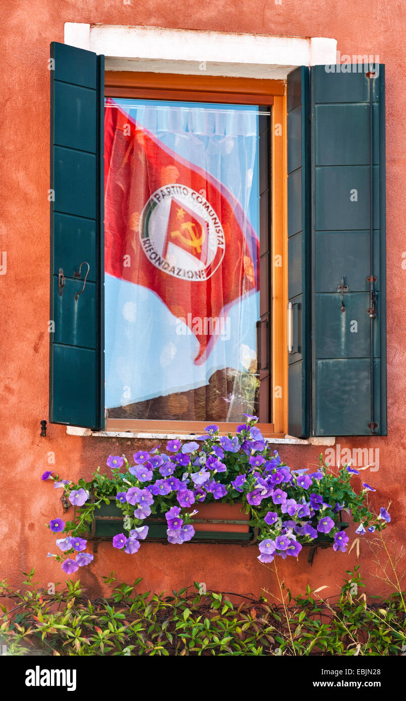 Venezia, Italia. Un Partito comunista italiano (PRC) bandiera il giorno di maggio (International giorno della festa dei lavoratori), che si riflette in una finestra Foto Stock