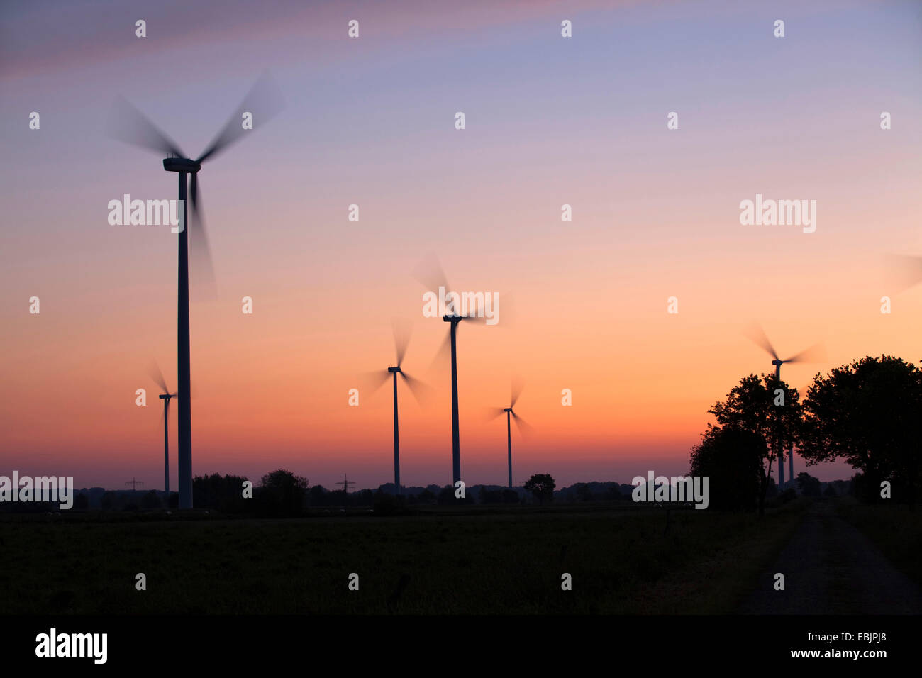 Sagome di un impianto di energia eolica a sunrise, Germania Foto Stock