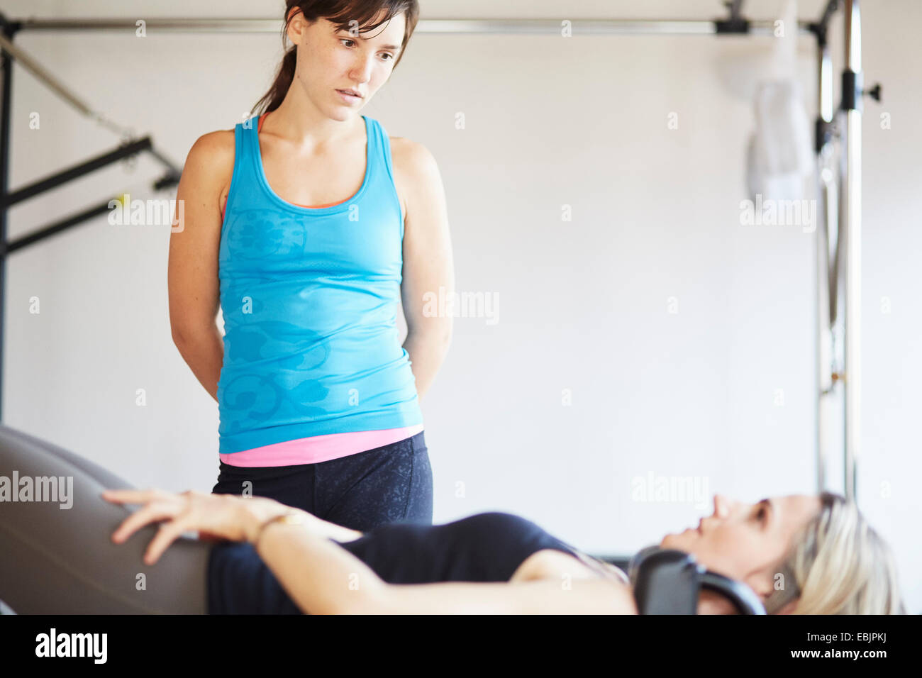 Femmina matura studente giacente sul tavolo trapezio in palestra pilates Foto Stock