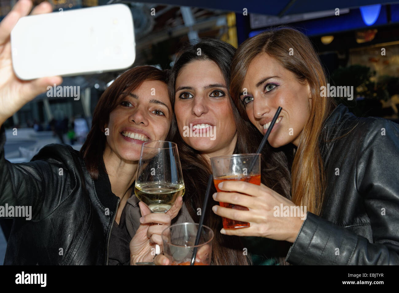 Tre amici di sesso femminile nel bar, tenendo autoritratto utilizza lo smartphone Foto Stock