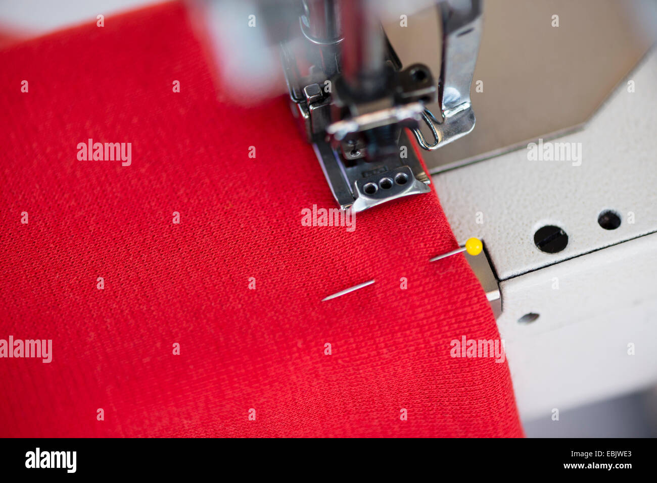Close up della macchina per cucire e rosso tessile in officina sarti da donna Foto Stock