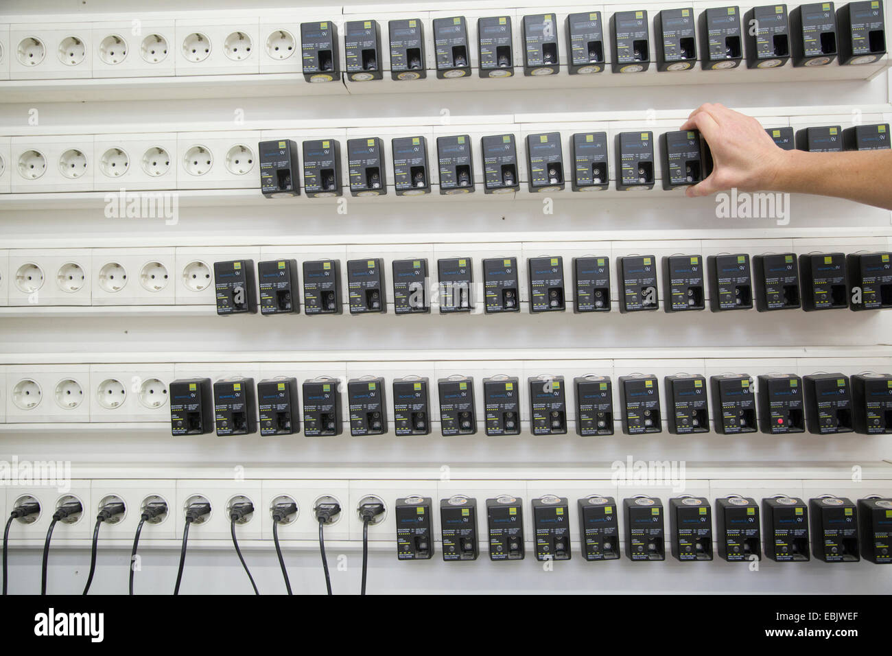 Lavoratore caricabatterie per batterie di test al magazzino di assistenza sanitaria Foto Stock
